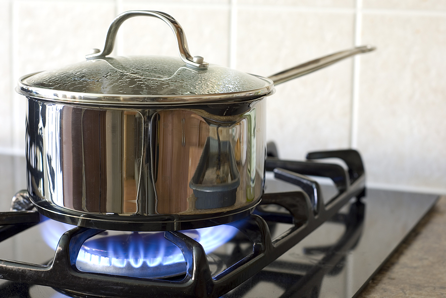A stainless steel pot on a natural gas stove.